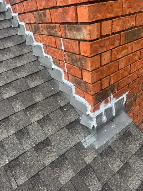 Newly sealed chimney with flashing and sealant on the roof.