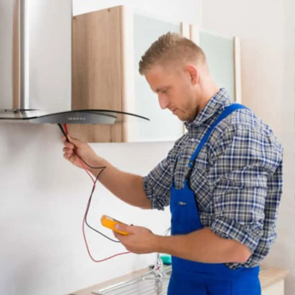 Technician using a multimeter to inspect a kitchen range hood.