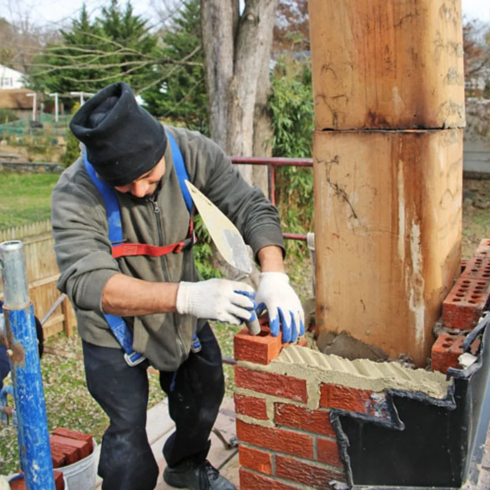 Chimney repairman laying bricks on a chimney structure.