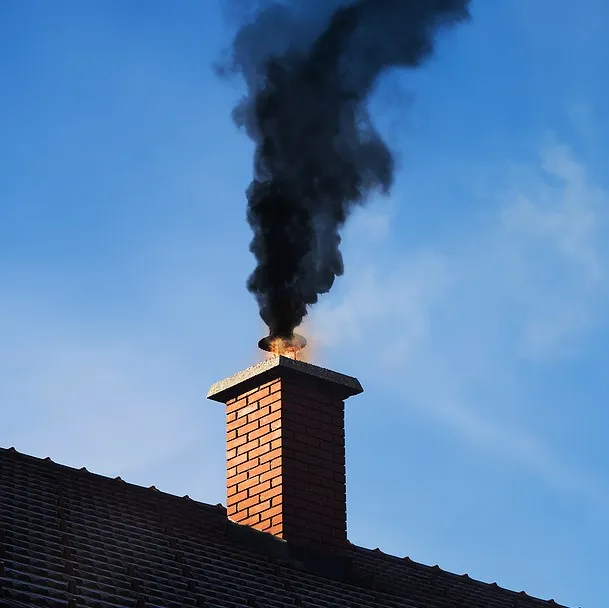 Chimney with black smoke coming out, indicating a problem with the chimney or the fire inside.